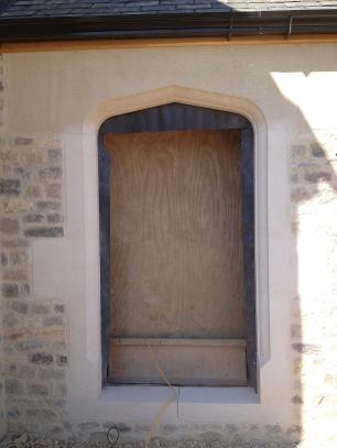 Bath stone arched doorway set in Purbeck stone walling .
